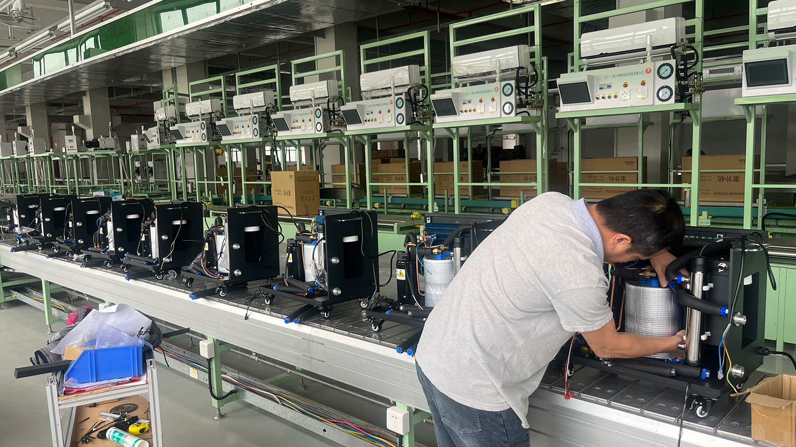 Technician fitting components inside an open chiller on the assembly line