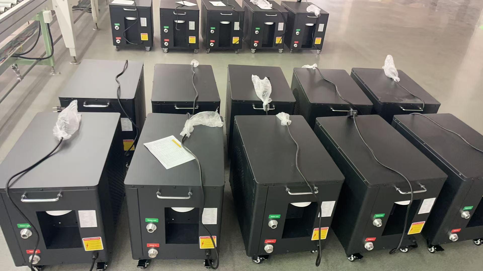Assembled black chillers grouped on the workshop floor with cables and fittings visible